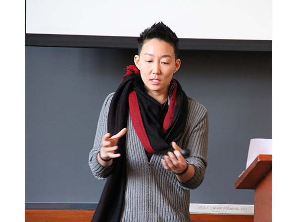 YK gesturing in front of a classroom